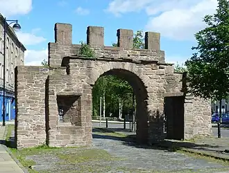 A colour photograph of an isolated stone gate surmounted by crenels