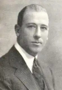 A white man with short hair and a receding hairline, wearing a suit and tie