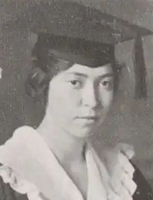 A young white woman with dark hair wearing a mortarboard cap and a white ruffled collar