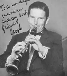 A portrait of Ernst Höllerhagen, a white man with dark hair, playing the clarinet.