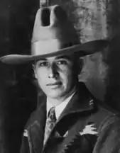 A young man in a cowboy hat, casual jacket, and shirt and tie