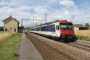 Red-white-and-blue train passes two-story building