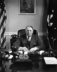 Male civilian sitting at a desk, with pen in hand