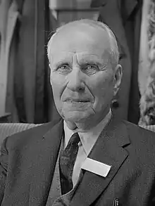 Black-and-white photo of gray-haired man in front profile wearing suit.