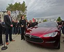 Musk converses with U.S. Senator Dianne Feinstein beside a red Tesla