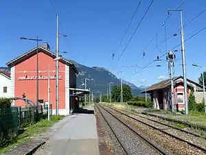 Two-story building with gabled roof next to double-tracked railway line