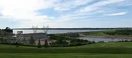 Side view of a dam surrounded by green hills under a clear sky