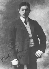 A black and white photograph showing an early middle-aged man with short, uncovered Afro-textured hair posing in a suit.