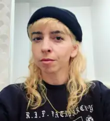 playwright and director gina young, in a black sweatshirt and beanie, with bleached blonde hair