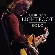 A photo of Lightfoot playing guitar onstage