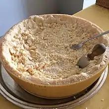 Half a wheel of Parmigiano Reggiano cheese served on a table.