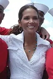 Head and shoulders shot of a smiling Berry with dark hair pulled back, wearing a lace shirt and turquoise necklace.