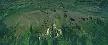 A long lightly glaciated mountain mass surrounded by vegetation.