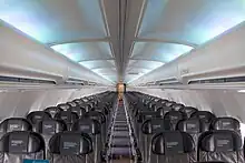 Cabin of the 757. There are six seats per row, with a single aisle separating the seats. Light shines through the side-wall windows and overhead lighting