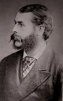 Black-and-white photographic portrait of a bearded gentleman in a suit