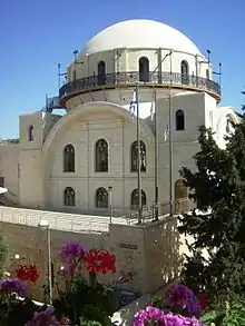 A tall, white bricked, domed building against a blue sky.