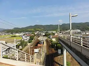 A view of the western (Kōtoku Line) platforms looking in the direction of Takamatsu. The station building is the red tiled building partly obscured by a section of footbridge to the right.