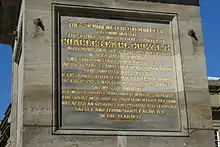 Inscription in gold text on the base of the stone monument.