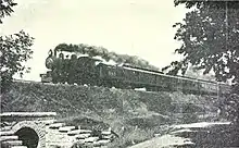 Steam locomotive with coaches on a raised embankment