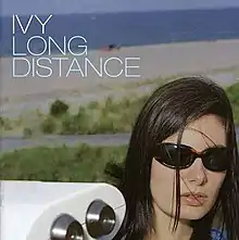 Lead singer Dominique Durand has head exposed wearing sunglasses, as she appears in front of a white car in a beach-like setting.