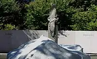 Statue of a crane in front of a wall with names of internment camps