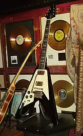 A color photograph of a black Gibson Flying V guitar