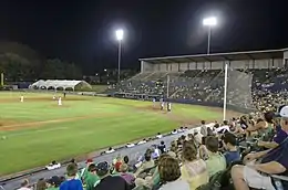 A view from the left field seats of the field and seating bowl at the stadim. Dark green seats stretch from behind first base, behind home plate, to third base.