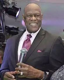 A man wearing a tuxedo is holding a microphone