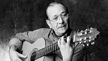 Guitarist Habichuela playing flamenco guitar, looking at left hand fingers, right hand thumb preparing apoyando ("rest stroke") attack on fifth string