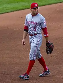 A baseball player wearing a gray uniform with a red cap and socks