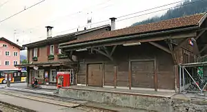 Two-story building with gabled roof and adjoining single-story wooden shed