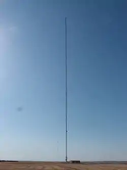 A very tall, guyed broadcast tower in a field