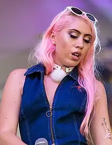 Photograph of Kali Uchis with pink hair and white sunglasses