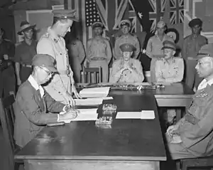 Two Japanese officers sitting at a desk during a surrender ceremony