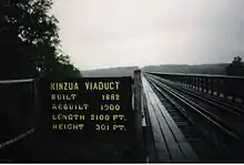 View across the bridge from the bridge deck. A sign indicating the bridge's construction year, reconstruction year, height and length is next to the bridge deck.