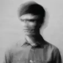 A blurred black and white picture of a man moving his head from left to right.