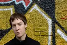 Chris Child standing in front of a graffitied wall