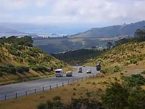 Dunedin-Waitati Hwy looking north from near the Pigeon Flat Overbridge. Blueskin Bay is visible in the background.