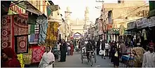 A very busy colorful street with many people walking along rows of little shops