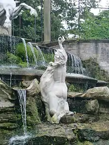 Colour photograph, rear view of marble statue of lady holding a pearl.