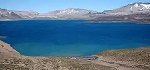 Laguna del Maule is a blue lake surrounded by barren and partially snow-covered mountains