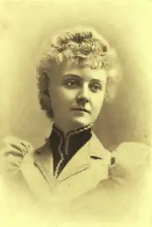 B&W portrait photo of a young blonde woman wearing a jacket with high collar and puffy sleeves.