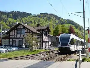 White train passes chalet-style building on the right