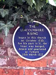 Plaque commemorating Lincolnshire Rising of 1536, opposite south entrance to church.