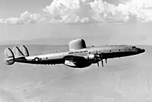 Black-and-white photograph of piston-engined aircraft with a large hump on midfuselage