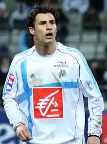 A footballer wearing a white jersey and white shorts