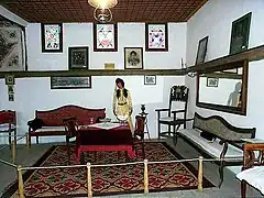 Living area with rug, table, two chairs and seating along the walls