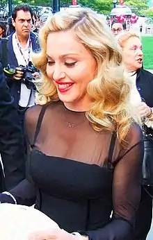 Madonna in a black dress, smiling and looking down