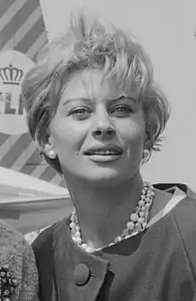 Black and white photograph of Magali Noël with short hair wearing pearl-like earings and necklace