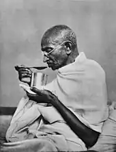 Black and white photo of Gandhi eating food.